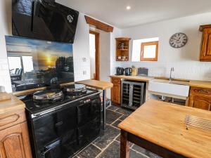 a kitchen with a black stove and a sink at Ceilwart Cottage in Barmouth