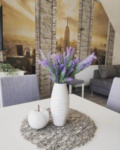 Un jarrón blanco con flores púrpuras y una vela sobre una mesa en Ferienwohnung Lavanda en Rust