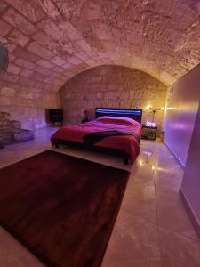 a bedroom with a bed in a stone wall at LA FORTERESSE - Jacuzzi/Sauna - Centre Historique in Rouen
