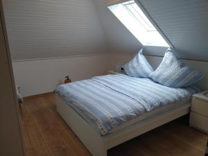 a bedroom with a bed with blue sheets and a window at Ferienwohnung StrandGut in Burhave