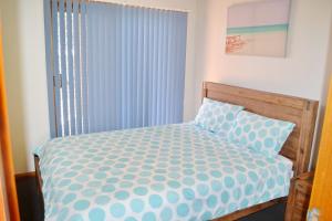 a bedroom with a bed with a blue and white comforter at Seaview Townhouse 3 in South West Rocks