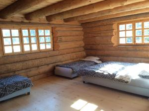 two beds in a log cabin with windows at Nadgora SkyHouse in Žabljak