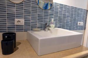 Casale Carratois - casa vacanze - Marzameni - Noto في بورتوبالو: بالوعة بيضاء في حمام به بلاط ازرق