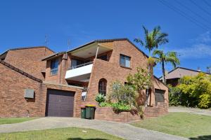 a brick house with a garage and a palm tree at Seaview Townhouse 1 in South West Rocks