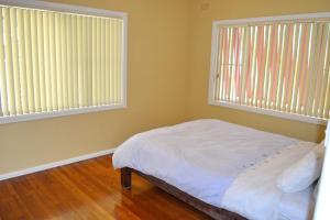 um quarto com duas janelas e uma cama com lençóis brancos em Seamist Cottage em South West Rocks