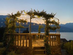 a wooden bench with a pergola with a view of the water at Casa Vittoria in Dervio