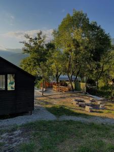 a black building with a group of logs next to trees at View Racha in Ambrolauri