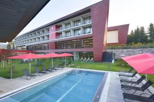 un hôtel avec une piscine dotée de chaises et de parasols dans l'établissement Spa Hotel Bründl, à Bad Leonfelden