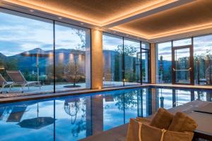 een huis met een zwembad en glazen wanden bij Historic Hotel Alte Goste in Valdaora