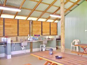 a large room with a kitchen with wooden tables at Coast and Country Cabin 4 