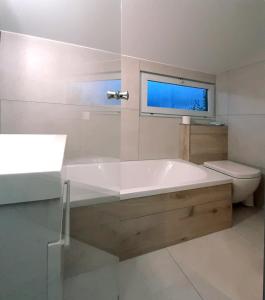 baño con bañera, aseo y ventana en Ferienhaus DANA, en Meschede