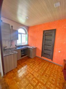 a large kitchen with orange walls and a wooden floor at Guest House in Sevan