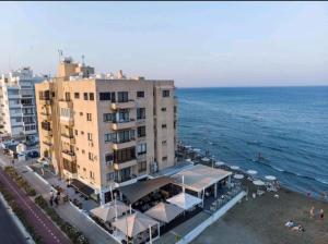 un edificio en la playa con el océano en el fondo en Bettys 1br seafront apt, en Lárnaca