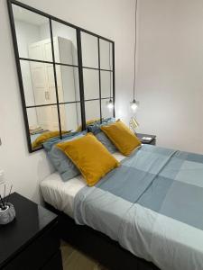 1 dormitorio con cama con almohadas amarillas y espejo en UIM Mediterraneo PB Luis Vives Wifi en Puerto de Sagunto