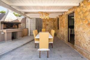 een eetkamer met een tafel en stoelen en een stenen muur bij Villa Tore in Quartu SantʼElena