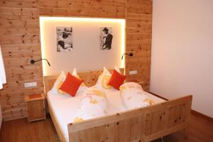 een slaapkamer met een houten bed met kussens bij Schneiderhof in Valdurna