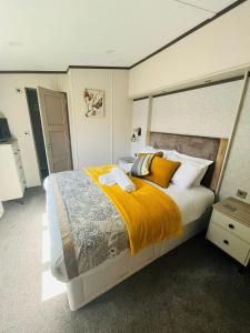 a bedroom with a large bed with yellow blankets and pillows at Laburnum Lodge with Hot Tub in York