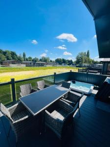 a table and chairs on a deck with a field at Laburnum Lodge with Hot Tub in York