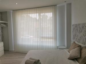 una camera da letto con una grande finestra con persiane verticali di Camiño da Praia a Redondela
