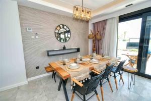a dining room with a table and chairs and a clock at Yedisu Villaları Family Only in Kemer
