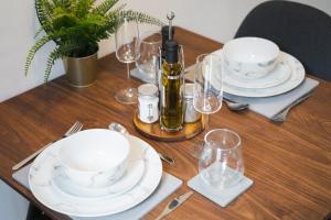 a wooden table with white plates and wine glasses at Modern 1-Bed Apartment - City Centre - FREE Wi-Fi - New - in Manchester