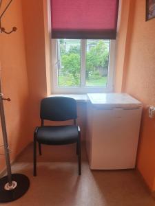 a chair sitting in a room with a window at Ukstiņa ielas apartamenti in Liepāja