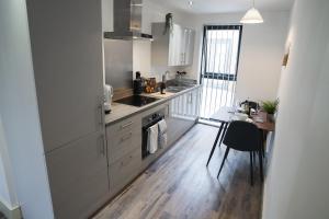 a kitchen with white cabinets and a table in it at Modern 1-Bed Apartment - City Centre - FREE Wi-Fi - New - in Manchester
