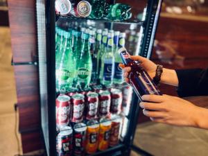 a person holding a bottle in front of a drink cooler at Hotel Hulaton Fukuokahakata in Fukuoka