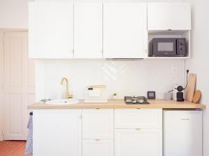 a kitchen with white cabinets and a sink and a microwave at Le Terracotta - Appartement centre ville avec balcon in Orange