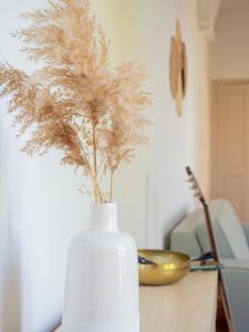 a white vase filled with dried grass on a table at Le Terracotta - Appartement centre ville avec balcon in Orange