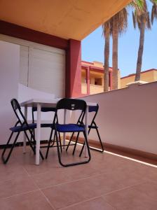 two chairs and a table on a patio with palm trees at Casa Guira - Fuerteventura in Parque Holandes