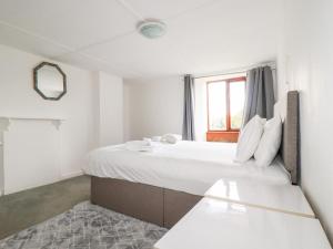 a large bed in a room with a window at Atlantic Farmhouse in Bude