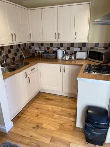 uma cozinha com armários brancos e piso em madeira em The Ashton Mews em Bristol