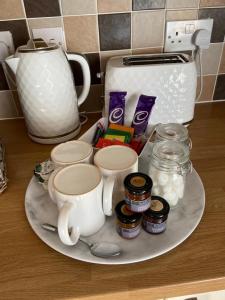 a plate with coffee cups and jams and a toaster at The Ashton Mews in Bristol