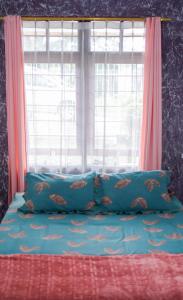 a bed with two blue pillows and a window at Vila murah di dekat kawasan wisata lembang in Citeureup 1