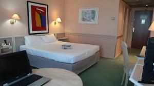 a hotel room with a bed and a desk with a laptop at Logis Lyon Est Porte de l'Ain in Saint-Maurice-de-Beynost