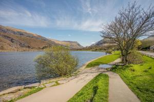 a path next to a lake with mountains in the background at Ty Bach - Llanberis in Caernarfon