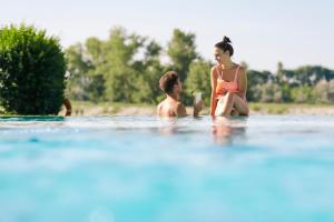 a woman and a boy are playing in the water at St. Martins Therme & Lodge in Frauenkirchen