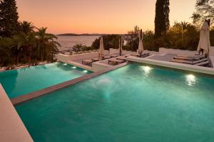 Una piscina con sillas y sombrillas junto al agua. en Hotel Moeesy, Blue & Green Oasis - Adults Only, en Hvar
