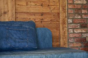 Dobra Chata Jaśkowo في فيارتيل: أريكة زرقاء في غرفة بجدار من الطوب