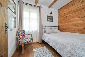 a bedroom with a bed and a chair and a window at Dobra Chata Jaśkowo in Wiartel