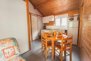 cocina con mesa, sillas y nevera en Village de Gîtes des Chalets du Camping du Golf, en La Canourgue