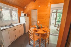 cocina con mesa con sillas y fregadero en Village de Gîtes des Chalets du Camping du Golf, en La Canourgue