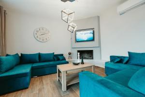 a living room with blue couches and a tv at Little Villa in Makrirrákhi