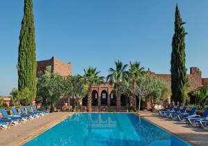 a swimming pool in a resort with chairs and trees at Kasbah Angour in Tahannout