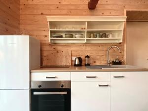 uma cozinha com armários brancos e um frigorífico branco em Hyggehytten auf Bornholm em Østermarie