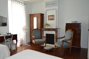 a living room with two chairs and a fireplace at La Vieille Distillerie in Le Tâtre