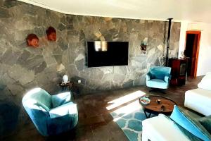 sala de estar con pared de piedra y TV en Charming Villa La Mar, en Albox