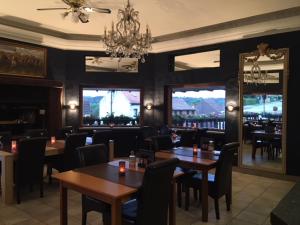 a restaurant with tables and chairs and a chandelier at Avalon Hotel in Overijse