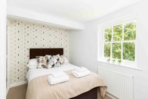 a white bedroom with a bed with two towels on it at The Old Morgan Period Apartments in Great Malvern